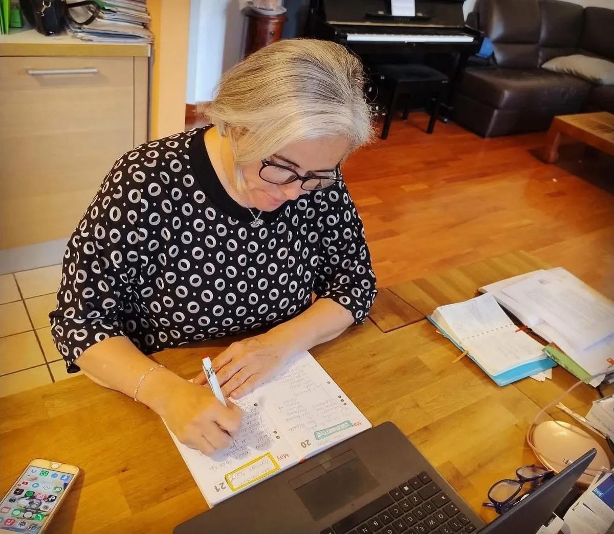 Sofia al tavolo di casa mentre organizza il lavoro, tra agenda e portatile