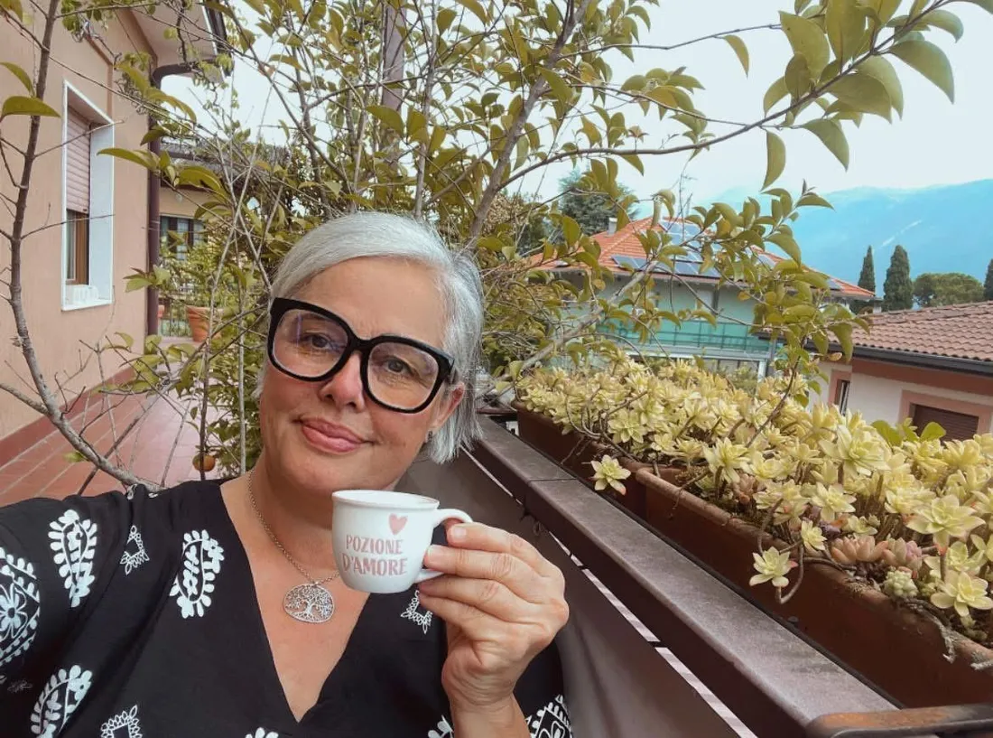 Sofia sul balcone di casa a Riva del Garda, con una tazzina di caffè